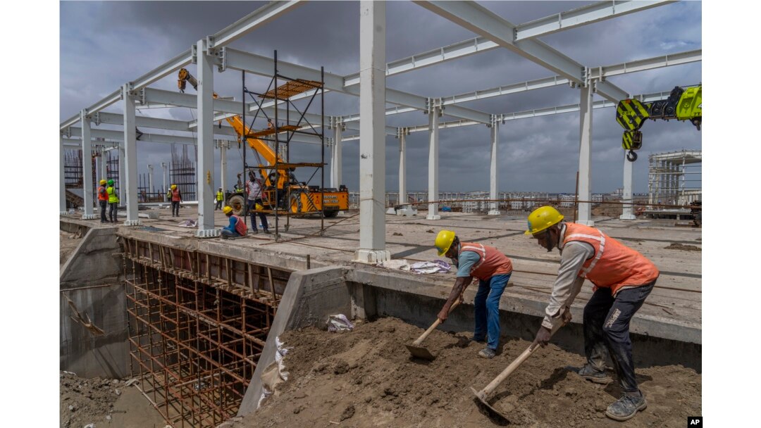 Employees work at the site of Adani Green Energy Limited's Renewable Energy Park in the salt desert of Karim Shahi village, near the India-Pakistan border in the western state of Gujarat, India, Thursday, Sept. 21, 2023. (AP Photo/Rafiq Maqbool)