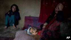 An internally displaced woman takes care of her sick child in a camp on the outskirts of Kabul, Afghanistan, Thursday, Feb. 9, 2023. She has no money to treat her sick child. (AP Photo/Ebrahim Noroozi)