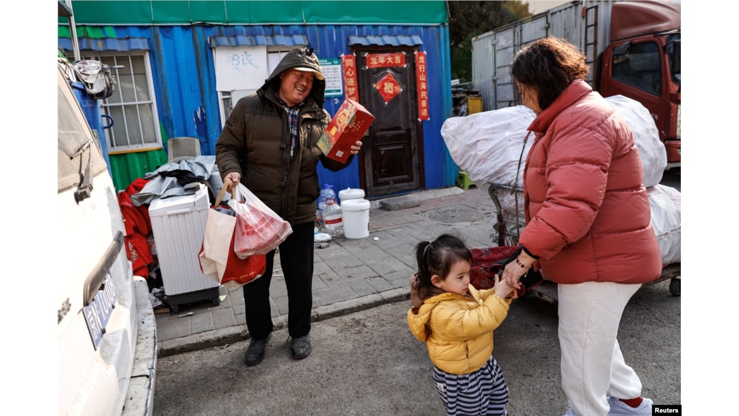 Wu Yonghou, 58, receives presents from a resident on Chinese Lunar New Year's Eve, at the recycling station where he and his wife work, in Beijing, China February 9, 2024. (REUTERS/Tingshu Wang)