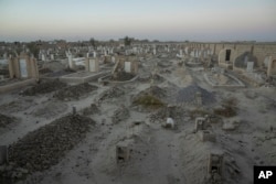 An Afghan Shiite cemetery, where a large number of Shiite migrants who were killed while trying to cross the border are buried, lies on the outskirts of Zaranj city, Afghanistan, Monday, Dec. 25, 2023. (AP Photo/Ebrahim Noroozi)