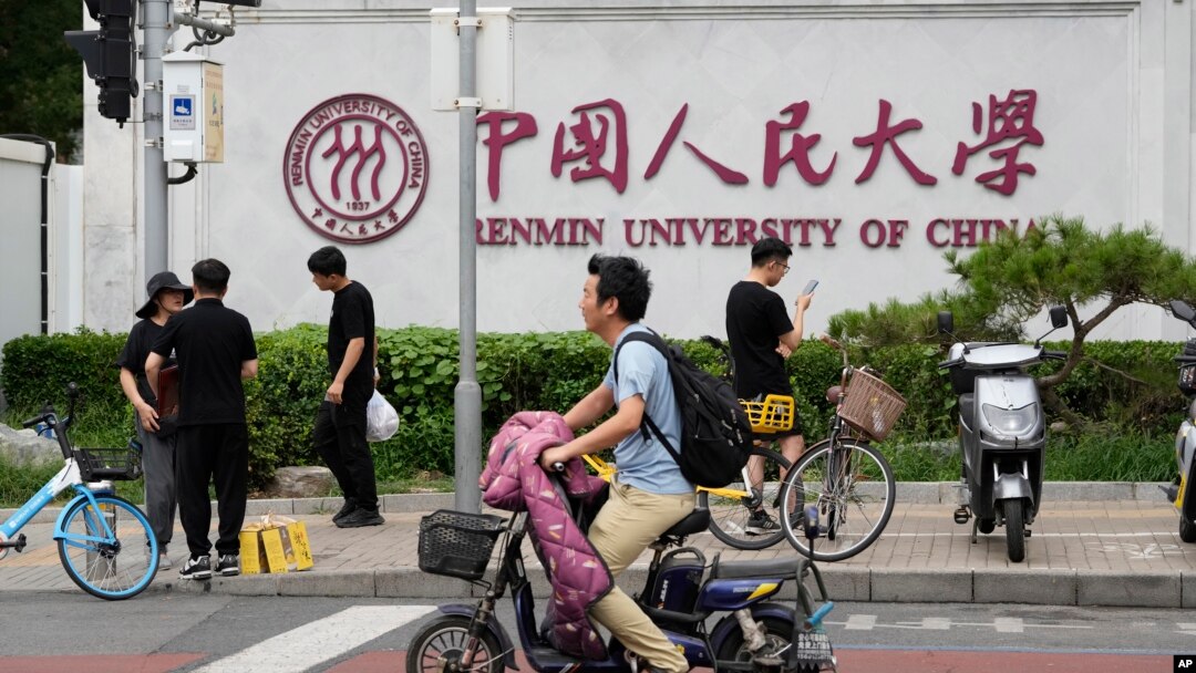 北京街頭大衆經過中國人民大學校園外牆的標誌。 （2024年7月22日）