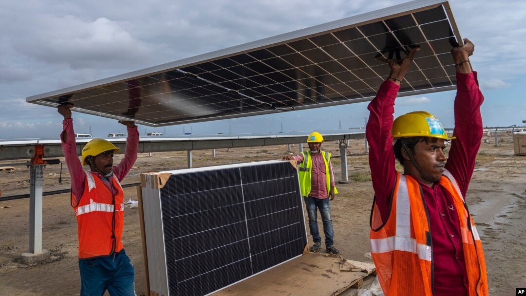 Workers carry a solar panel for installation at the under-construction Adani Green Energy Limited's Renewable Energy Park in the salt desert of Karim Shahi village. (AP Photo/Rafiq Maqbool)