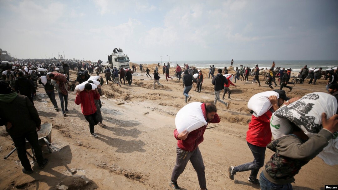Wapalestina wakibeba magunia ya unga waliyopora kwenye lori la misaada