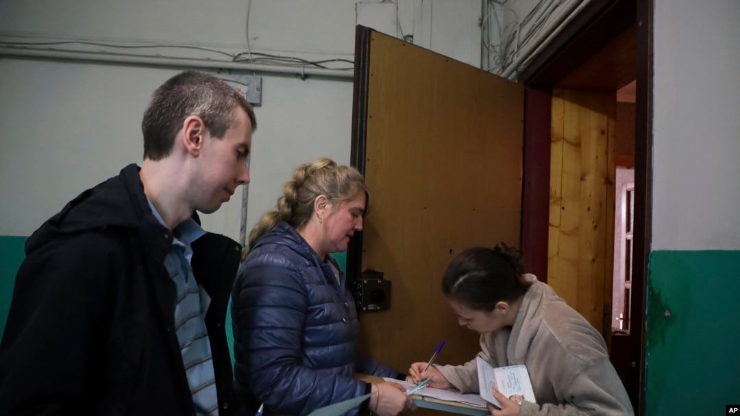Članovi biračkog odbora pomažu ženi da glasa tokom referenduma u Marijupolju, u Donjeckoj Narodnoj Republici, koju kontrolišu proruski separatisti, u istočnoj Ukrajini, 26. septembra 2022.