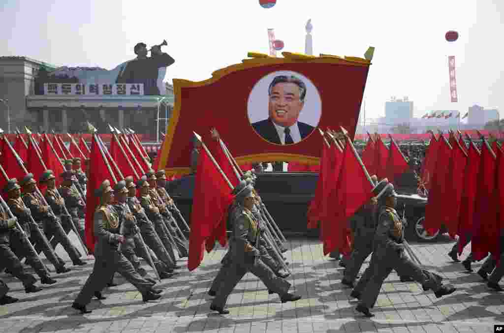 朝鲜军人扛着红旗，在平壤金日成广场簇拥着金日成巨像参加阅兵式(2017年4月15日)。