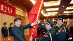 中共领导人习近平在北京举行的中国人民解放军战区成立大会上向火箭军将领、中国防长魏凤和（中）授予军旗。（2015年12月31日）