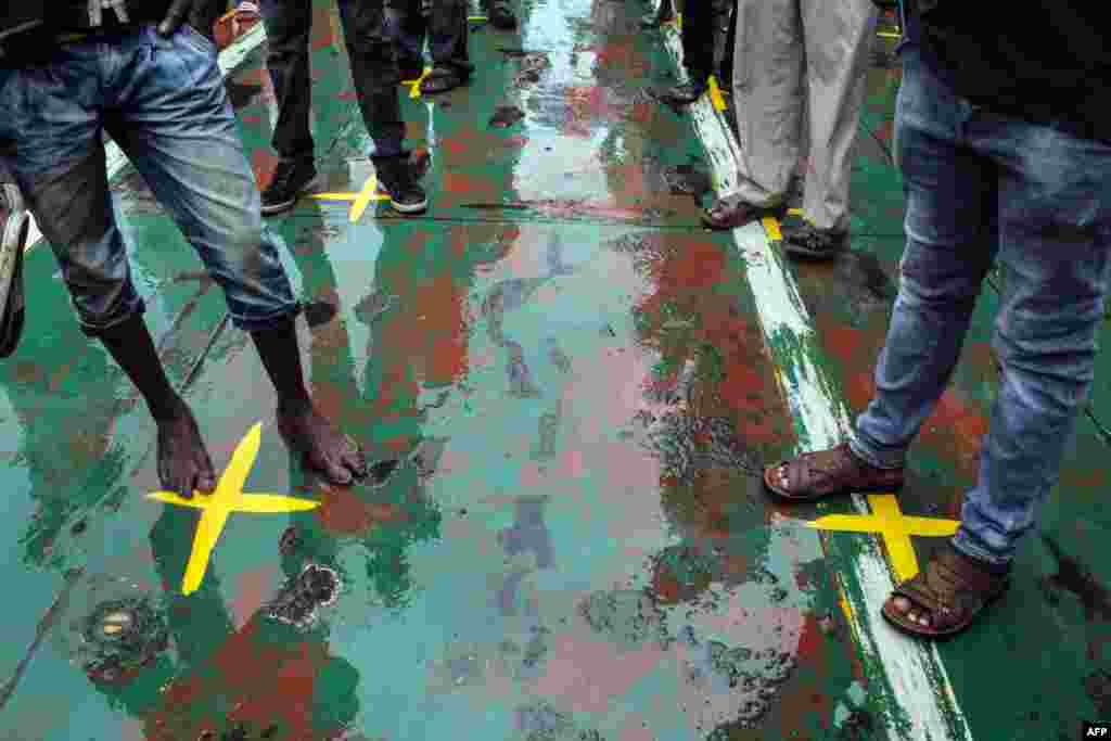 Commuters stand on yellow marks that indicate the physical distancing recommended to curb the COVID-19 coronavirus from spreading, on a ferry at Likoni ferry terminal, in Mombasa, Kenya.