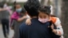 People carrying children wearing face masks to help curb the spread of the coronavirus head to a kindergarten in Beijing on June 9, 2021.