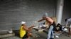 Un miembro de un grupo de residentes del barrio marginal de Chapeu Mangueira, en Brasil, rocía alcohol en la mano de una persona sin hogar mientras le entrega comida en la playa de Copacabana en Río de Janeiro, el 11 de abril de 2020.