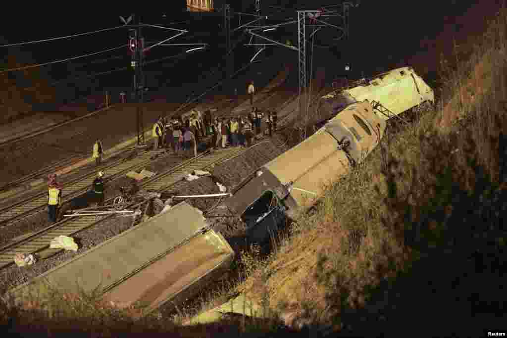 Rescue workers and officials are seen amongst the wreckage of the train crash near Santiago de Compostela, northwestern Spain, early July 25, 2013. 