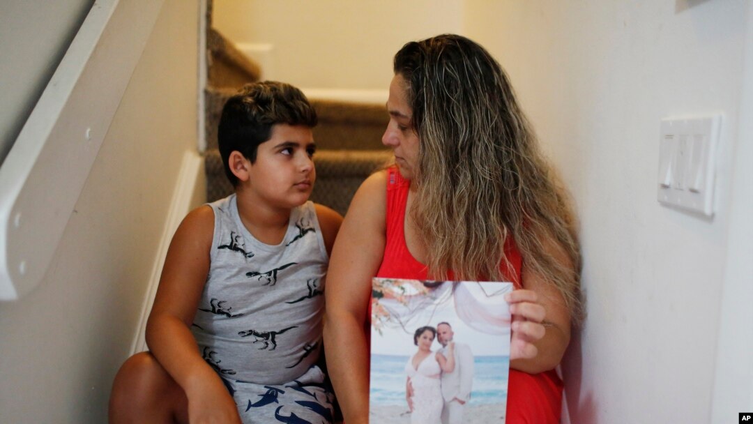 Barbara Rodriguez and her son, Nolan Aragon, 9, pose for a photograph in Hialeah, Fla., Aug. 6, 2019. Rodriguez is holding a wedding photograph of her and her husband, Pablo Sanchez, who is in detention in the U.S. and facing deportation to Cuba.