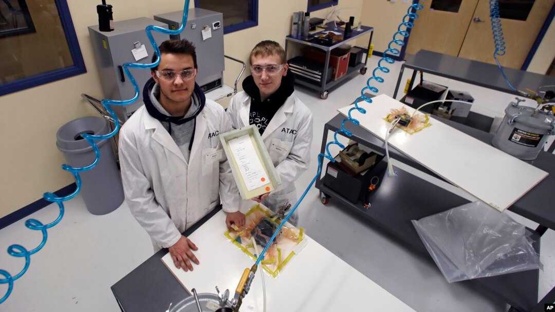 FILE - High School students P.J. Perkins, left, and Dylan DiBernardo in a manufacturing lab at Great Bay Community College in Rochester, N.H. Jan. 4, 2019 where they study for manufacturing certificates. (AP Photo/Charles Krupa)