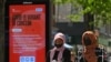 FILE - Pedestrians walk past a sign warning members of the public about a "Coronavirus variant of concern," in Hounslow, west London, Britain, June 1, 2021.