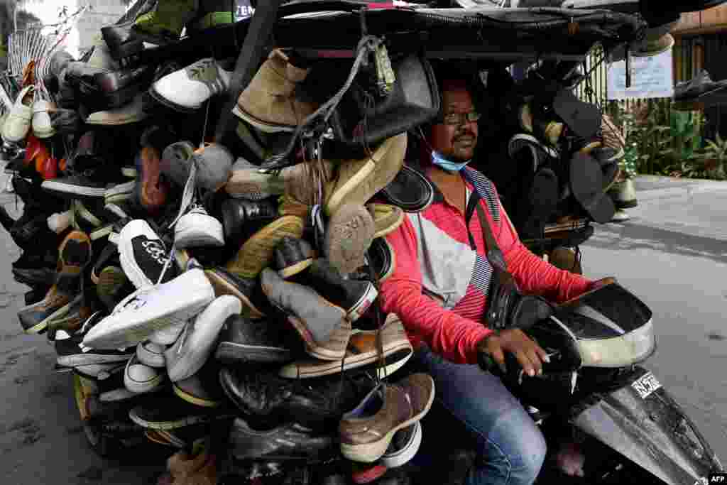 A man rides a motorcart loaded with secondhand shoes for sale on a street in Phnom Penh, Cambodia.
