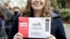 ARCHIVO - Una mujer en Seattle, Washington, muestra el sobre donde porta su boleta de voto por correo durante las elecciones del candidato presidencial por el partido demócrata. Febrero 22, 2020.