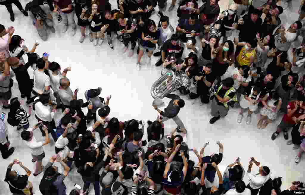A man holds up a tuba as protesters shout slogans and sing Hong Kong&#39;s anthem during a protest at New Town Plaza shopping mall in Hong Kong, China.
