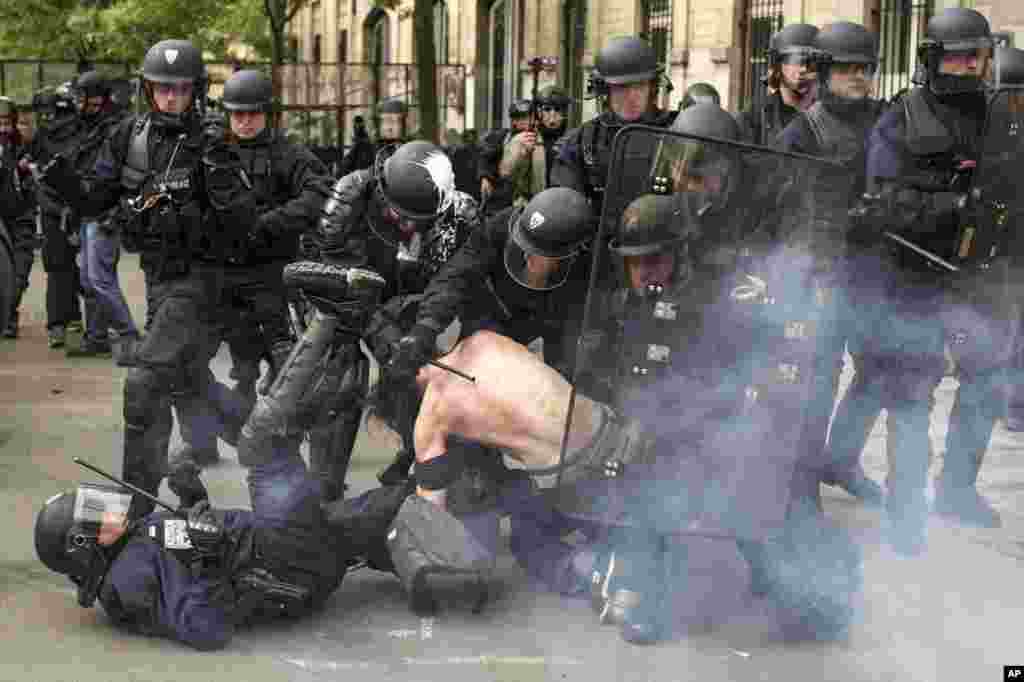French riot police officers detain a man during a demonstration against a labor law bill, in Paris.