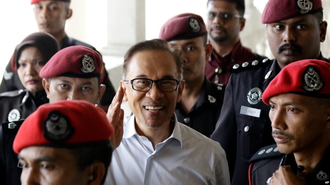 FILE - Deputy Prime Minister and opposition leader Anwar Ibrahim, center, smiles as he arrive at court house in Kuala Lumpur, Malaysia, June 13, 2017.