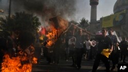 Manifestantes iraníes queman representaciones de las banderas israelí y estadounidense en una concentración antiisraelí en la plaza Felestin (Palestina) en Teherán, Irán, el martes 8 de octubre de 2024.