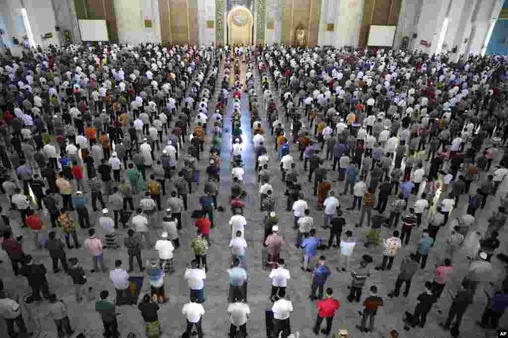 Muslim men perform Friday prayer at the distance of about one meter (3 ft) to each other as a social distancing effort to prevent the spread of new coronavirus outbreak at Al Akbar mosque in Surabaya, East Java, Indonesia.