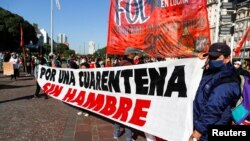 Manifestantes despliegan una pancarta que lee "Por una cuarentena sin hambre", durante una protesta para demandar recursos para los más vulnerables durante la crisis de la pandemia en Buenos Aires, Argentina. Mayo 2020.