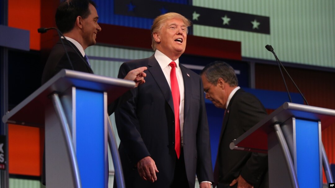 Republican presidential candidates, from left, Scott Walker, Donald Trump, and Jeb Bush are seen during a break at the first Republican presidential debate at the Quicken Loans Arena, Aug. 6, 2015, in Cleveland. 