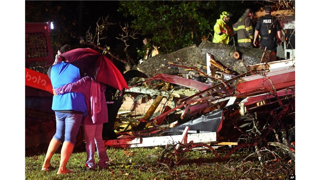 Los transeúntes se abrazan mientras los socorristas trabajan para liberar a una víctima después de que un árbol cayera sobre una casa en Natchez, Mississippi, el sábado 28 de diciembre de 2024. (Thomas Graning/The Natchez Democrat vía AP)