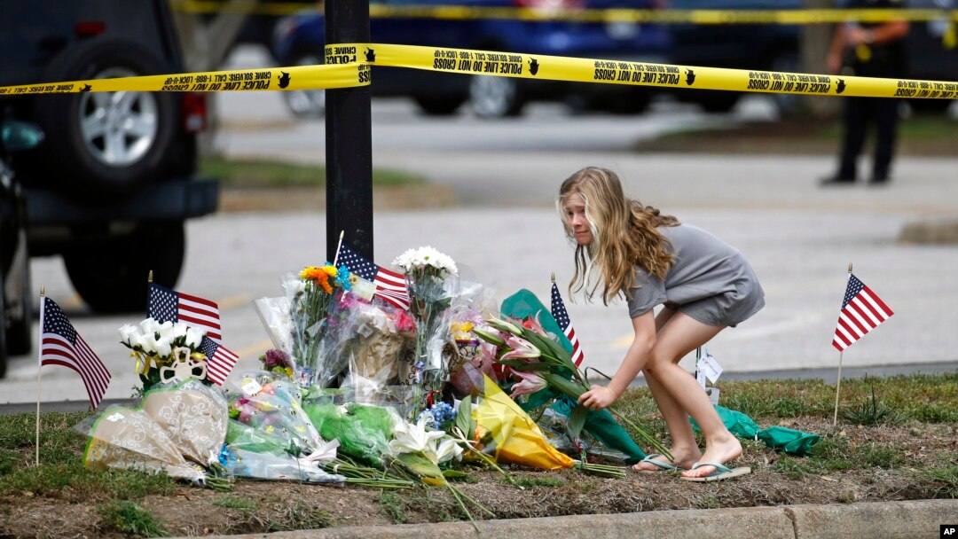 Una niña deja un ramo de flores en un altar dedicado a las víctimas del tiroteo en Virginia Beach, al filo de un cordón policial frente al edificio municipal donde ocurrió la tragedia. Enero 1, de 2019.