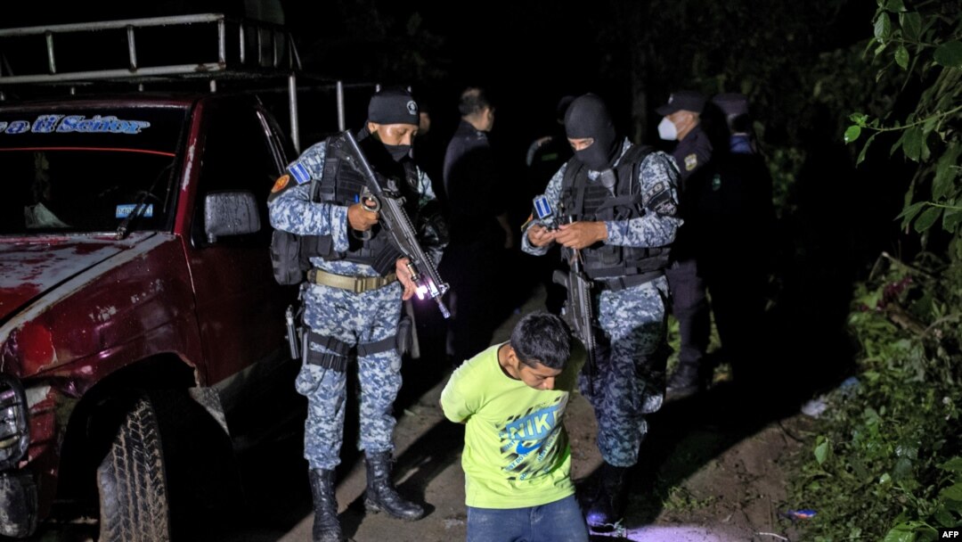 Un presunto pandillero permanece arrodillado mientras es detenido por agentes de la sección táctica operativa (STO) de la Policía Nacional Civil el 29 de octubre de 2020 en la madrugada, en San Marcos, El Salvador.