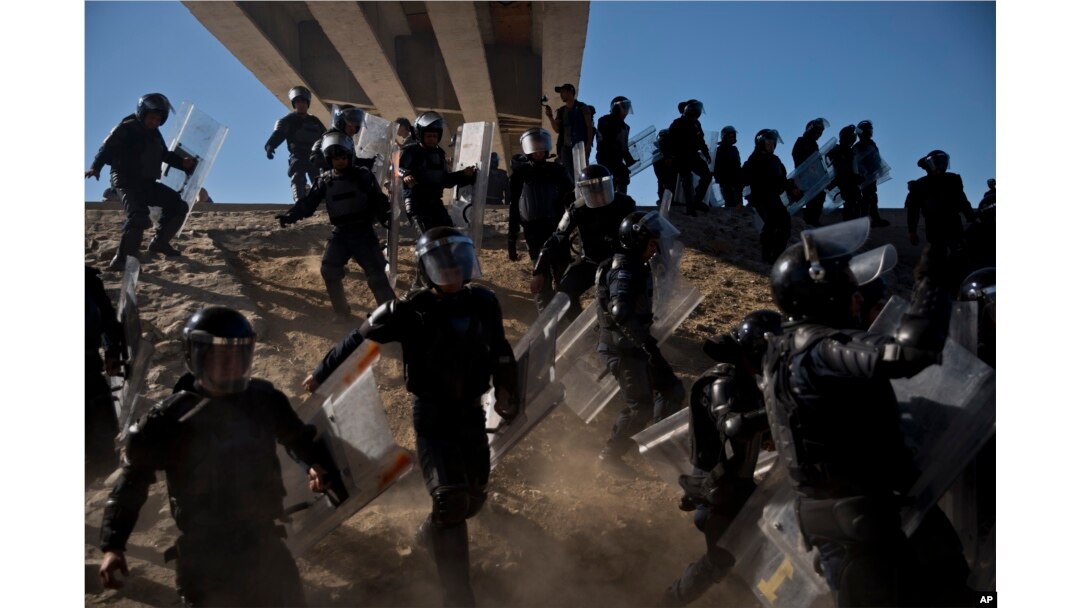 Mexican police run as they try to keep migrants from getting past the Chaparral border crossing in Tijuana, Mexico, Sunday, Nov. 25, 2018, near San Ysidro, California.