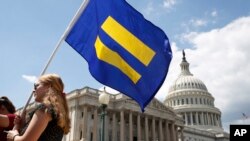 一名LGBT权利支持者举着“平等旗”参加民主党众议员乔·肯尼迪的集会，抗议特朗普总统不许跨性别者服役的禁令。(2017年7月26日）