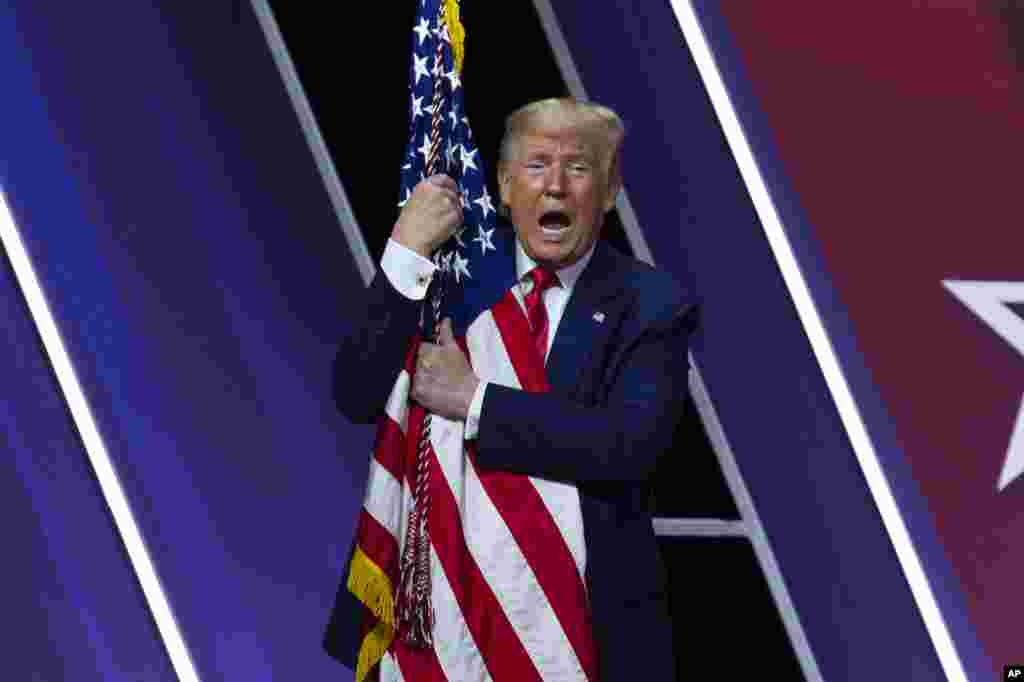 President Donald Trump hugs and kisses the American flag after speaking at Conservative Political Action Conference, CPAC 2020, at the National Harbor, in Oxon Hill, Maryland, Feb. 29, 2020.