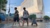 Residents walk along a flooded road in the aftermath of the heaviest recorded rainfall in Zhengzhou in central China's Henan province on July 24, 2021.