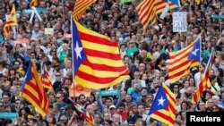 Manifestantes agitan banderas separatistas catalanas durante una manifestación organizada por los movimientos independentistas catalanes, tras el encarcelamiento de sus dos líderes Jordi Sánchez y Jordi Cuixart, en Barcelona, el 21 de octubre de 2017.