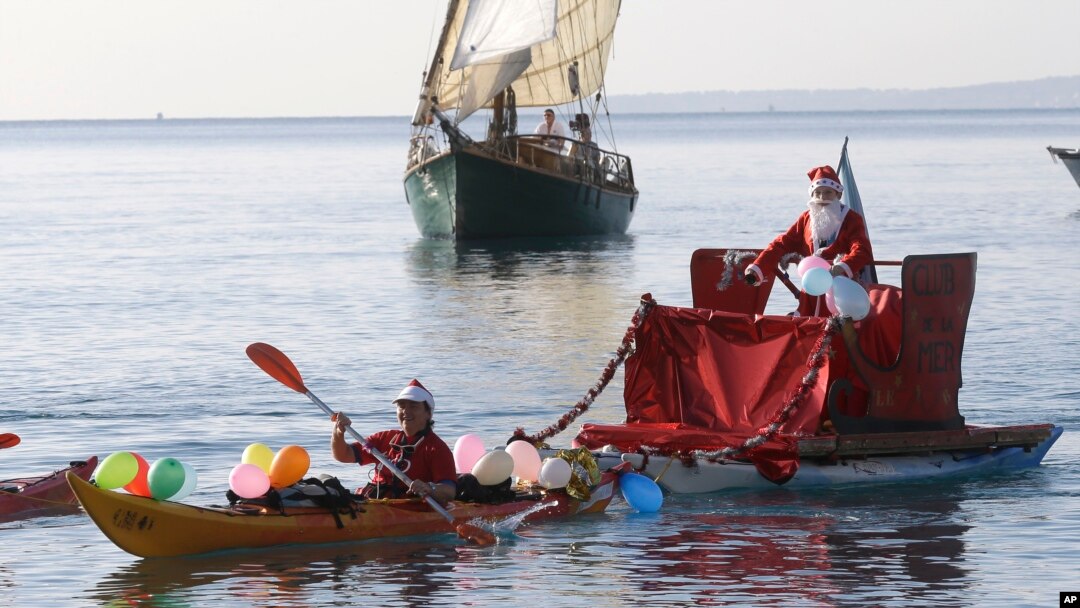 A man dressed as a Santa Claus rides a float pulled by a kayaker, on the Mediterranean sea during the traditional Christmas bath at Nice, southeastern France, Sunday, Dec. 20, 2015. (AP Photo/Lionel Cironneau)
