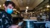 Restaurant host Joey Tyler verifies a patron's vaccination card at French restaurant Petit Trois in Los Angeles, California, Nov. 5, 2021.