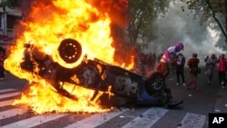 Menifestantes queman un auto policial durante una protesta de hinchas de fútbol y jubilados que exigen pensiones más altas y se oponen a las medidas de austeridad implementadas por el gobierno de Javier Milei. En Buenos Aires, Argentina, el miércoles 12 de marzo de 2025.