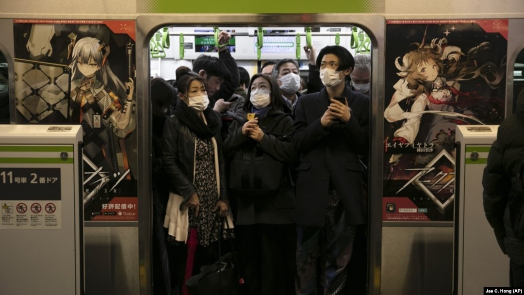 In this March 2, 2020, file photo, commuters wearing masks stand in a packed train at the Shinagawa Station in Tokyo. (AP Photo/Jae C. Hong, File)