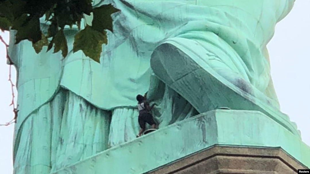 Una manifestante es vista en la base de la Estatua de la Libertad en Nueva York, el 4 de julio de 2018.