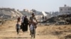 Palestinos recorren un camino bordeado de edificios destruidos en el campamento de Al Bureij, en el centro de la Franja de Gaza, el 2 de junio de 2024, en medio del conflicto en curso entre Israel y el grupo militante palestino Hamás.
