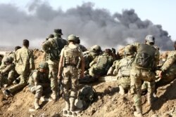 FILE - Turkish troops and Turkish-backed Syrian rebels gather outside the border town of Ras al-Ayn on Oct. 12, 2019,during their assault on Kurdish-held border towns in northeastern Syria.