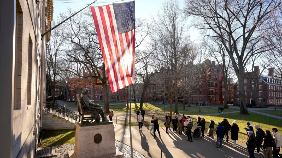 ARCHIVO - Personas tomando fotografías cerca de una estatua de John Harvard, izquierda, en el campus de la Universidad de Harvard, el martes 2 de enero de 2024, en Cambridge, Massachusetts.