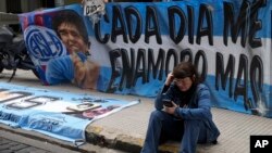 Un fanático del fallecido astro del fútbol Diego Maradona se sienta cerca de una bandera con su imagen afuera del tribunal donde los miembros del equipo médico que atendió a Maradona serán juzgados por presunto homicidio, en Buenos Aires, Argentina, el 11 de marzo de 2025. AP