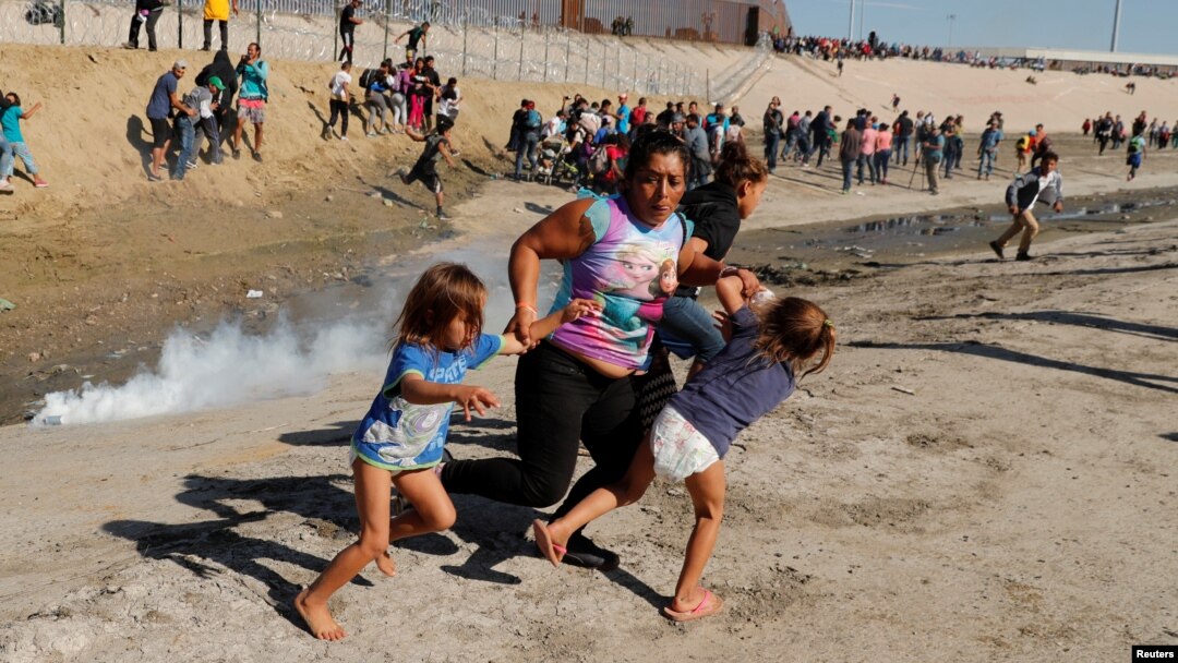 A migrant family, part of a caravan of thousands traveling from Central America en route to the United States, run away from tear gas in front of the border wall between the U.S and Mexico in Tijuana, Mexico November 25, 2018. REUTERS/Kim Kyung-Hoon 