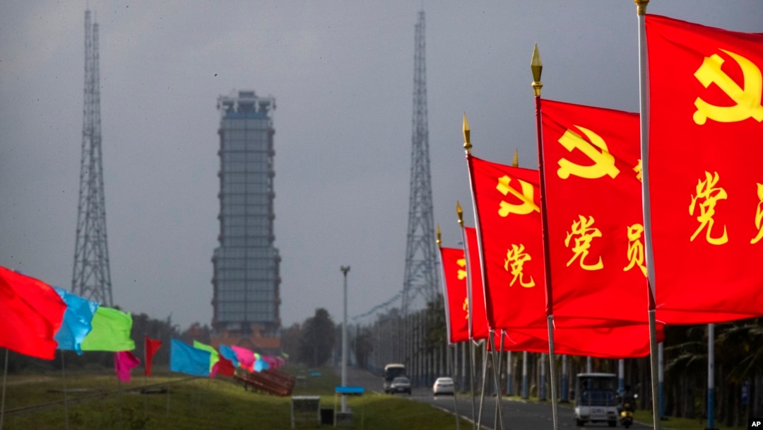 Flags with the logo of the Communist Party of China fly in the breeze near a launch pad at the Wenchang Space Launch Site in Wenchang in southern China's Hainan province, Monday, Nov. 23, 2020. (AP Photo/Mark Schiefelbein)