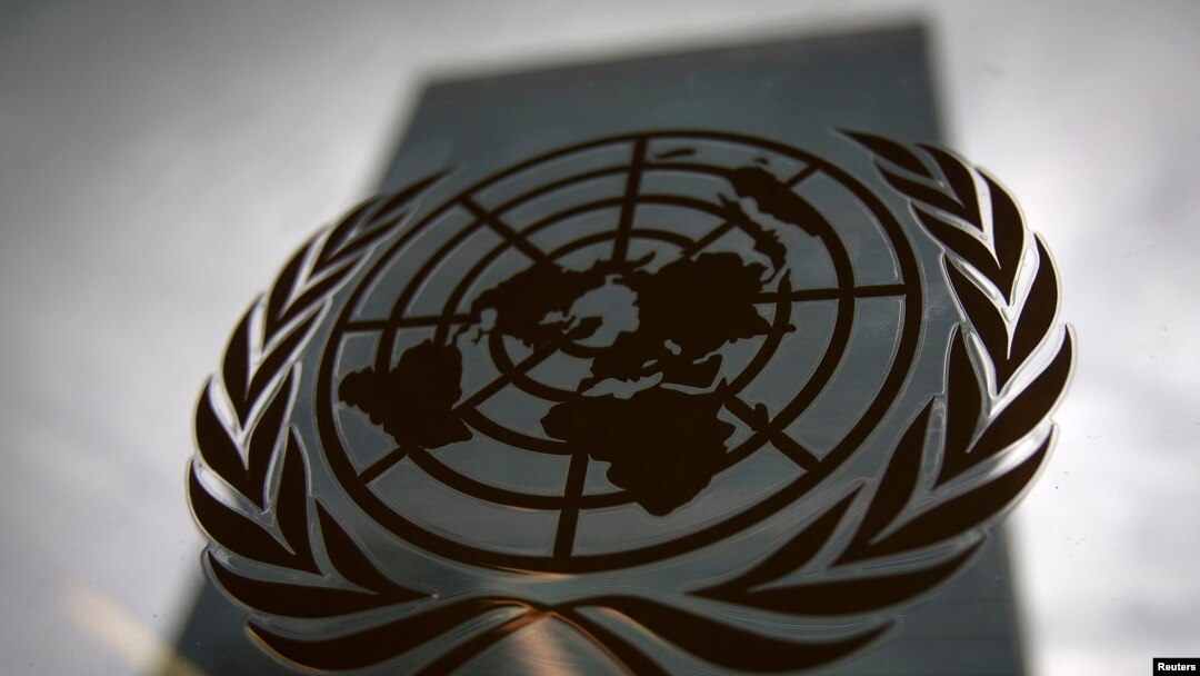 FILE - The United Nations headquarters building is pictured though a window with the UN logo in the foreground.