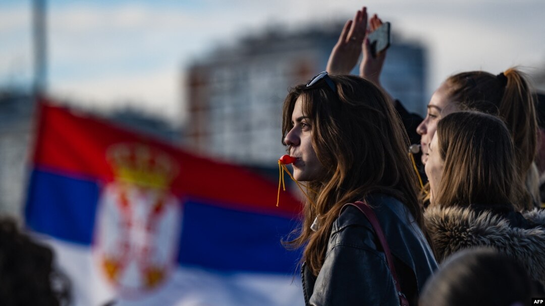 Studentkinja na protestnoj blokadi Autokomande, dok se srpska zastava vijori u pozadini (Foto: AFP/Andrej ISAKOVIC)