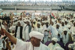 FILE - Supporters of Sudanese General Mohamed Hamdan Dagalo, also known as Himediti, deputy head of Sudan's ruling Transitional Military Council (TMC), raise up their sticks during a meeting with the General in the capital Khartoum, June 18, 2019.