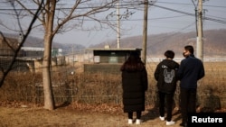 资料照：2021年2月12日，在韩国农历新年到来之际，一名脱北者和他的孩子们站在京畿道坡州市非军事区附近的铁丝网前。（路透社）