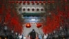 Un guardia de seguridad con mascarilla camina por la calle Quanmen, normalmente popular entre los turistas pero que aparece casi vacía, en Beijing, el domingo 16 de febrero de 2020. (AP Foto/Andy Wong)